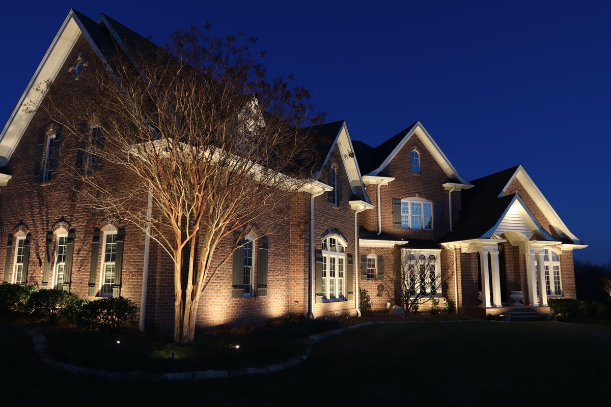 Brick house at night illuminated by landscape lighting