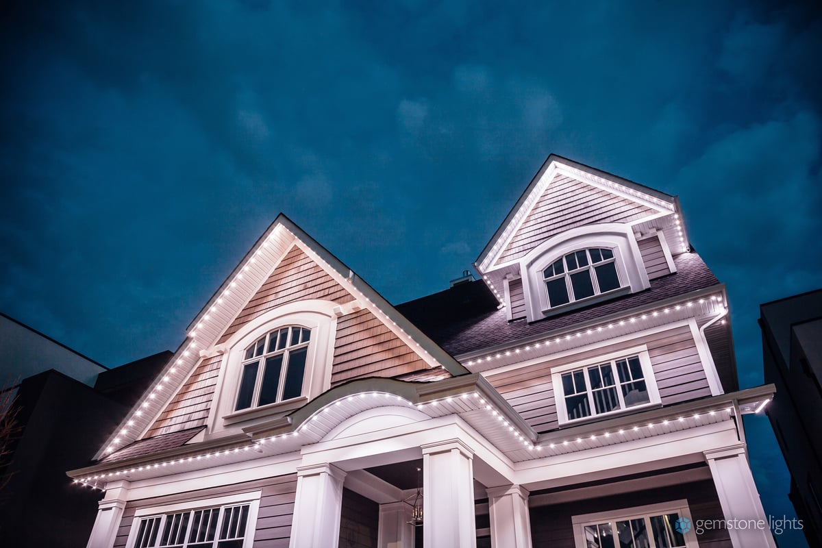 Roofline peaks of a house featuring white holiday lights