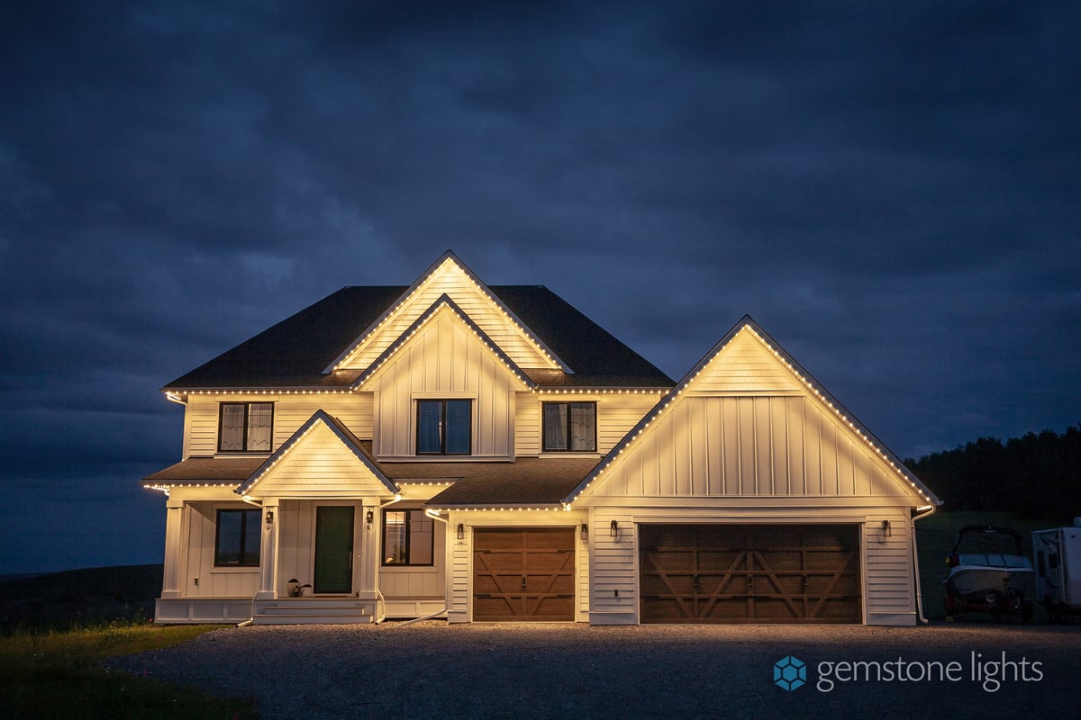 White farmhouse with warm white roofline lighting